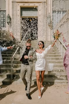 a bride and groom are walking down the stairs with confetti in their hands