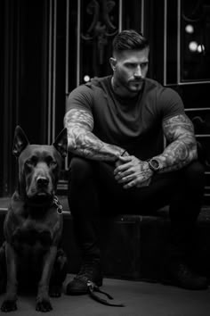 a man with tattoos sitting next to his dog