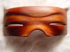 a wooden mask is laying on a white furnishing area and looks like it has been made out of wood