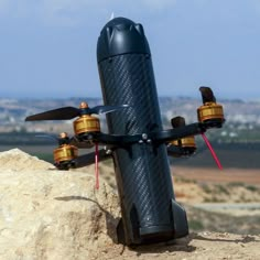 a black and gold remote control airplane sitting on top of a rock in the desert