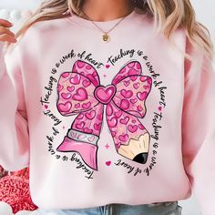 a woman wearing a pink sweatshirt with a large bow and hearts on the front that says i love you