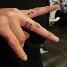 a person's hand with a small tattoo on it that reads 13 and has the number thirteen