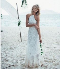 a woman standing on top of a sandy beach next to a palm tree in front of the ocean