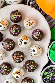 chocolate covered donuts decorated with sprinkles on a plate next to halloween decorations