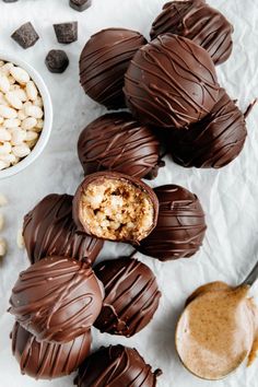 chocolate covered peanut butter balls on parchment paper with spoon and bowl of peanuts in the background