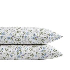 two white pillows with blue and green flowers on them, one is made from cotton