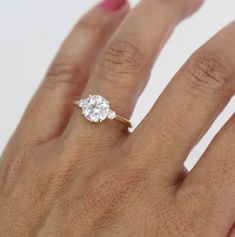 a woman's hand with a diamond ring on top of her finger and the other hand holding an engagement ring