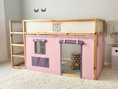 a child's play house made out of wood and pink fabric with purple curtains