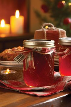 two jars filled with red liquid sitting on top of a table next to a christmas tree