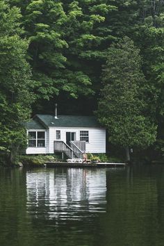 an image of a house on the water with trees in the backgroung