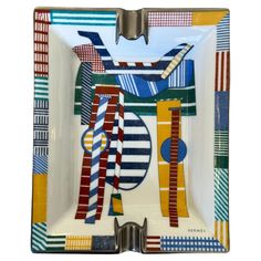 a square plate with an abstract design on the front and sides, in multicolored stripes