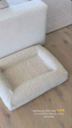 a dog bed sitting on top of a hard wood floor next to a white couch