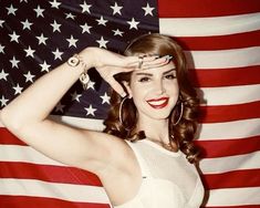 a woman posing in front of an american flag with her hands on her head and one hand over her eyes