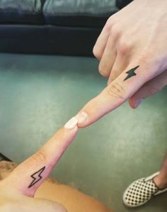 two people with matching tattoos on their fingers pointing at each other's fingernails