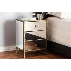 a mirrored nightstand next to a bed in a room with hardwood floors and white walls