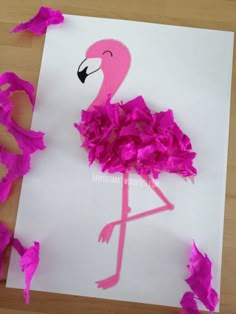 a pink flamingo is on a piece of white paper with purple shredded paper around it