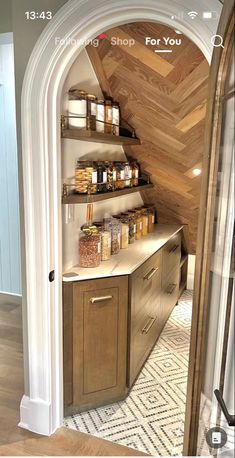 the inside of a kitchen with shelves and jars on it's sides, in front of an arched doorway