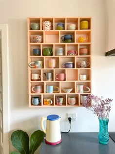 a wooden shelf filled with lots of cups and vases on top of a table