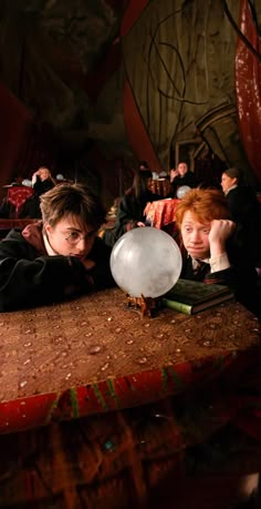 two people laying down on a table with a balloon in front of them and one person looking at the camera