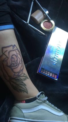 a person with a rose tattoo on their arm next to a box of lipstick and eye shadow