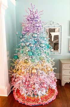 a multicolored christmas tree with ornaments on it in the corner of a room