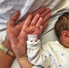 a baby is being held by someone's hand with a name tag on it