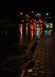 cars are driving down the street in the rain at night with their lights turned on