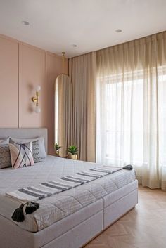 a bedroom with pink walls and white bedding in front of a window covered by drapes