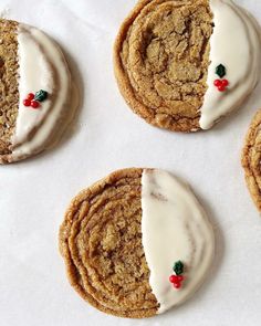 four cookies with white icing and holly decorations on them are arranged next to each other