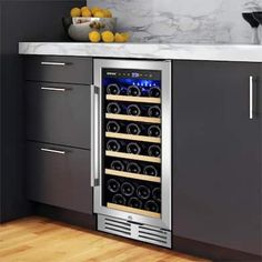 a stainless steel wine cooler in the corner of a kitchen with marble counter tops and gray cabinets