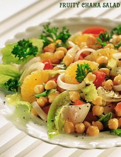 a white plate topped with salad and garnished with oranges, lettuce and chickpeas