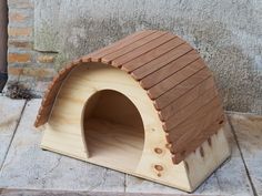 a small wooden dog house sitting on the ground next to a brick wall and door