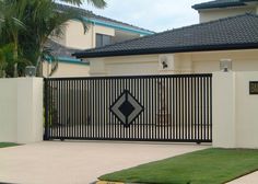 a black and white sign on a gate in front of a house with palm trees