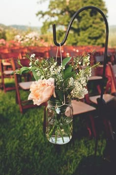 a vase filled with flowers sitting on top of a grass covered field next to chairs