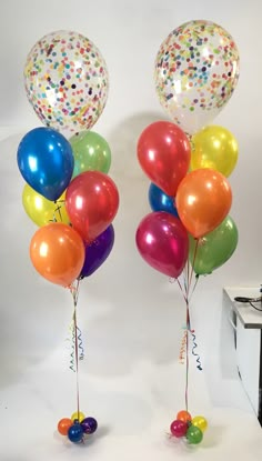 two balloons with streamers and confetti on them are standing next to each other