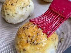 a red spatula is being used to spread cheese on top of bread buns