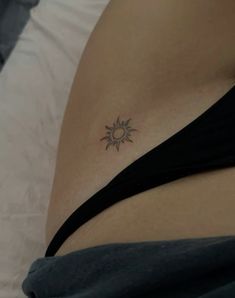 a woman's stomach with a small sun tattoo on her left side ribcage