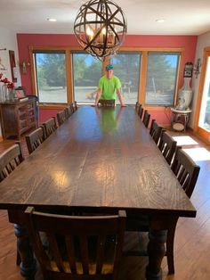 a man sitting at a large wooden table in a room with lots of windows and chairs