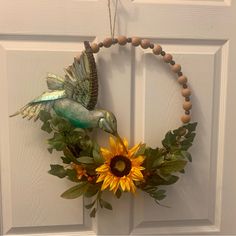 a wreath with a bird and sunflower hanging on the front door to welcome guests