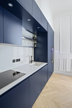 an empty kitchen with blue cabinets and white counter tops is seen in this image from the hallway