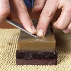 a person using a knife to cut something on top of a piece of brown material