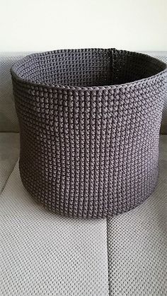 a gray basket sitting on top of a white couch