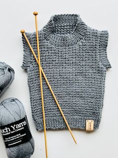 the knitting kit is next to some yarn and two skewers with needles on them