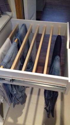 an open drawer with clothes and jeans in it