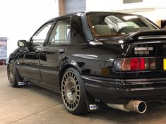 the rear end of a black car parked in a garage