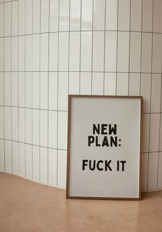 a sign that says new plan fock it on the floor next to a tiled wall