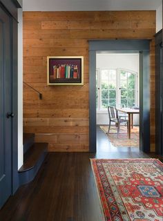 an entryway with wood paneling, blue doors and a rug on the floor