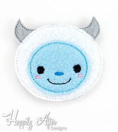 a blue and white felt brooch with horns on it's head is shown