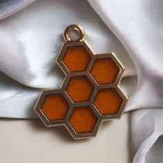 an orange hexagonal pendant hangs from a white satin