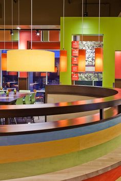 the interior of a brightly colored restaurant with round tables and colorful lights hanging from the ceiling